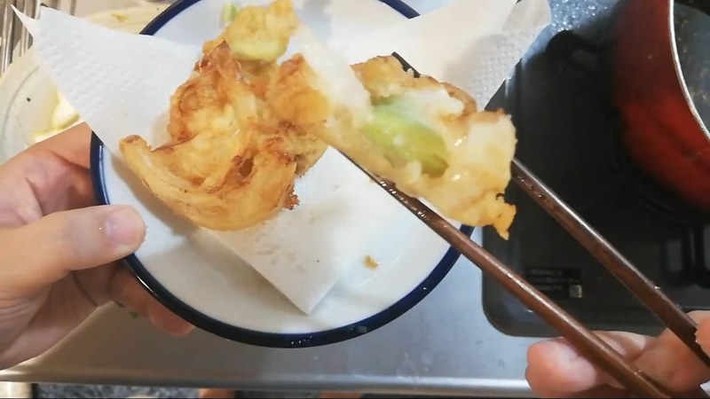 揚げたての天ぷらを箸でつまむ布団ちゃん