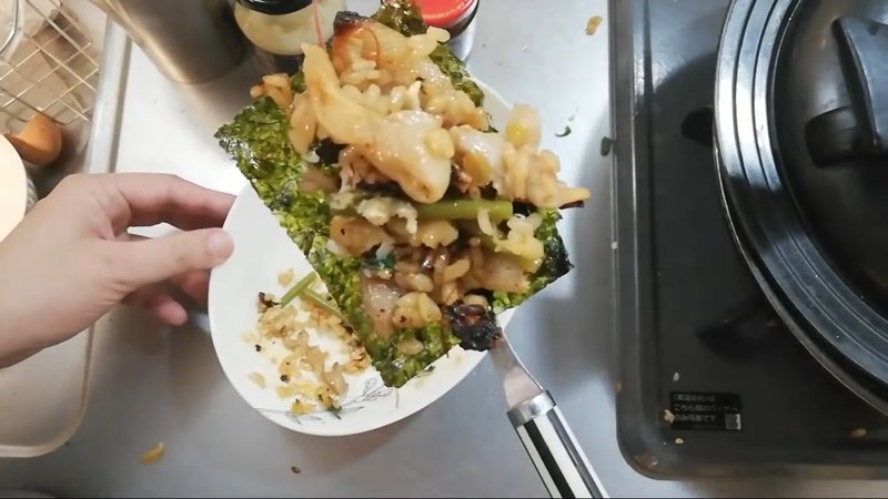 できあがったハイパーコリアンポークパエリアをスプーンですくい、韓国海苔と一緒に頬張る一コマ