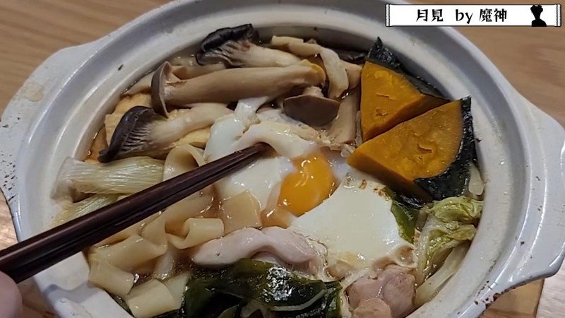 箸で卵の黄身を持ち上げ、崩れた月見卵ときしめんを掲げる瞬間